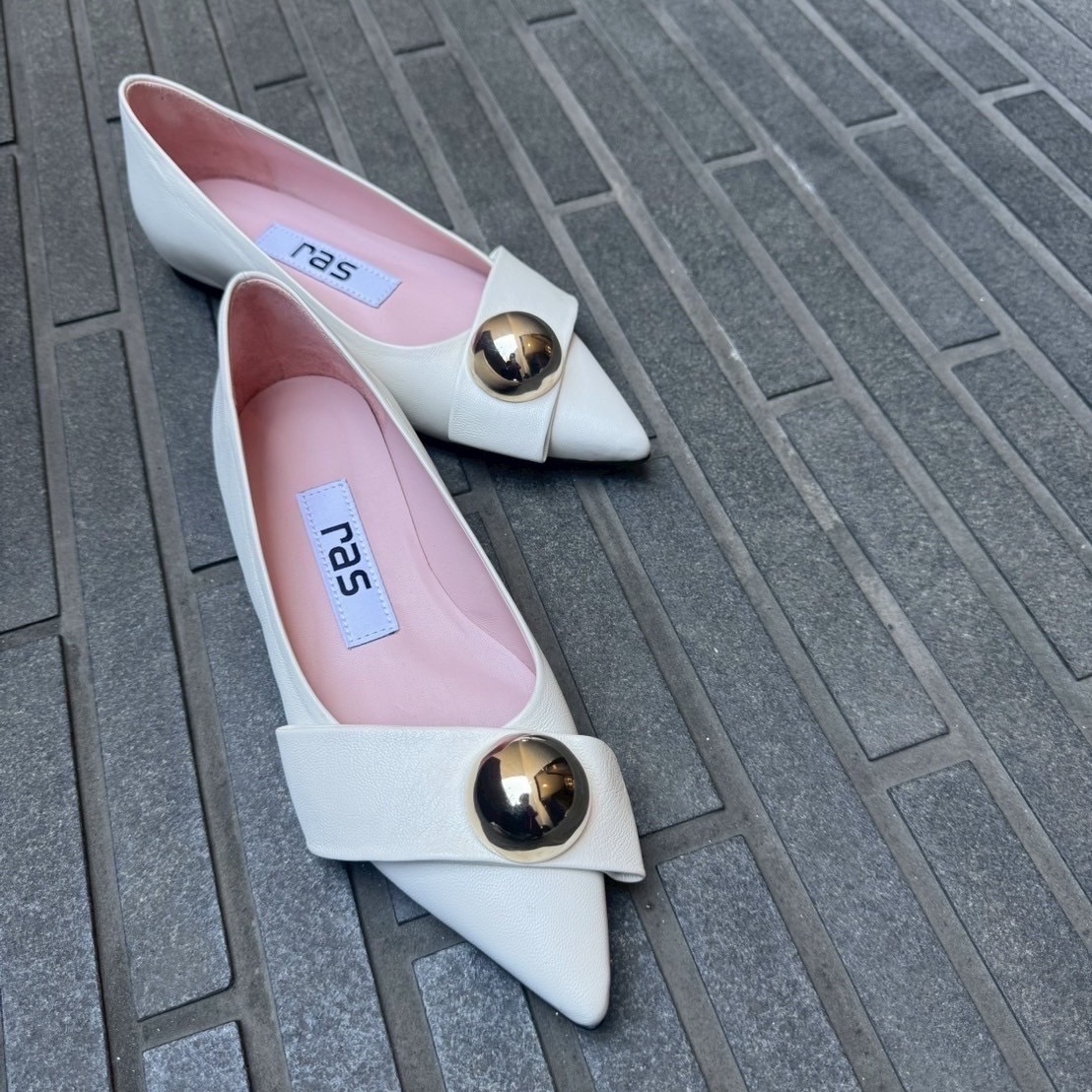 11/16ゴールドのボールパーツが目を引くホワイトカラーのフラットシューズ